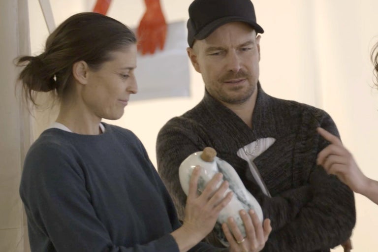 Personen betrachten eine dekorative Flasche mit Verschluss.