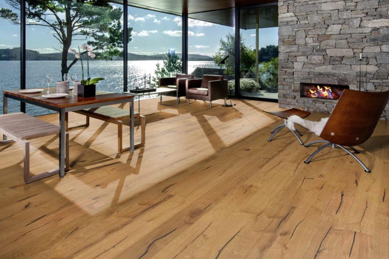 Wohnraum mit Holzboden, Esstisch, Stühlen, Kamin und Seeblick