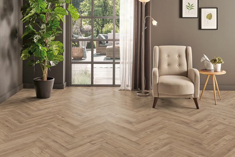 Wohnzimmer mit Fischgrätenparkett, Sessel und Zimmerpflanze