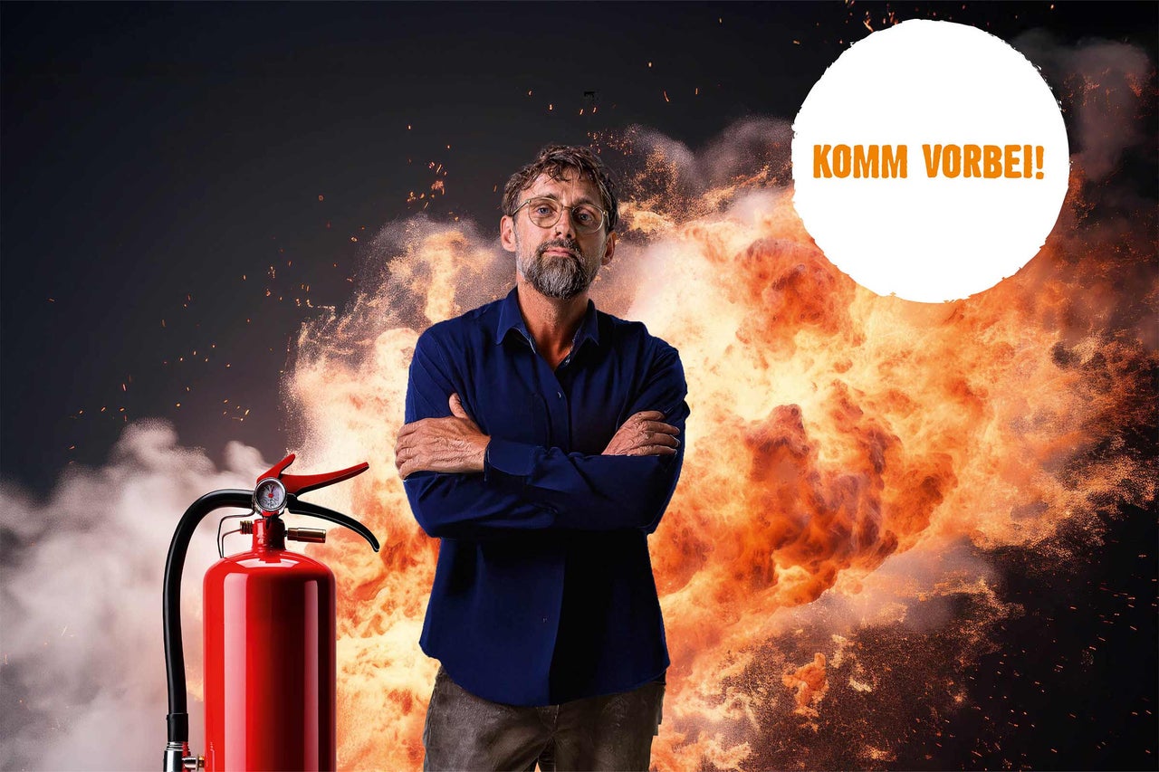 Mann mit verschränkten Armen vor Explosion und Feuerlöscher. Aufforderung: Komm vorbei!