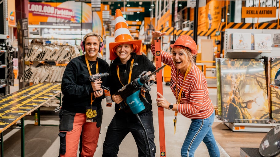 Drei Frauen posieren mit Werkzeugen in einem Hornbach Markt, eine trägt einen Verkehrskegel als Hut.