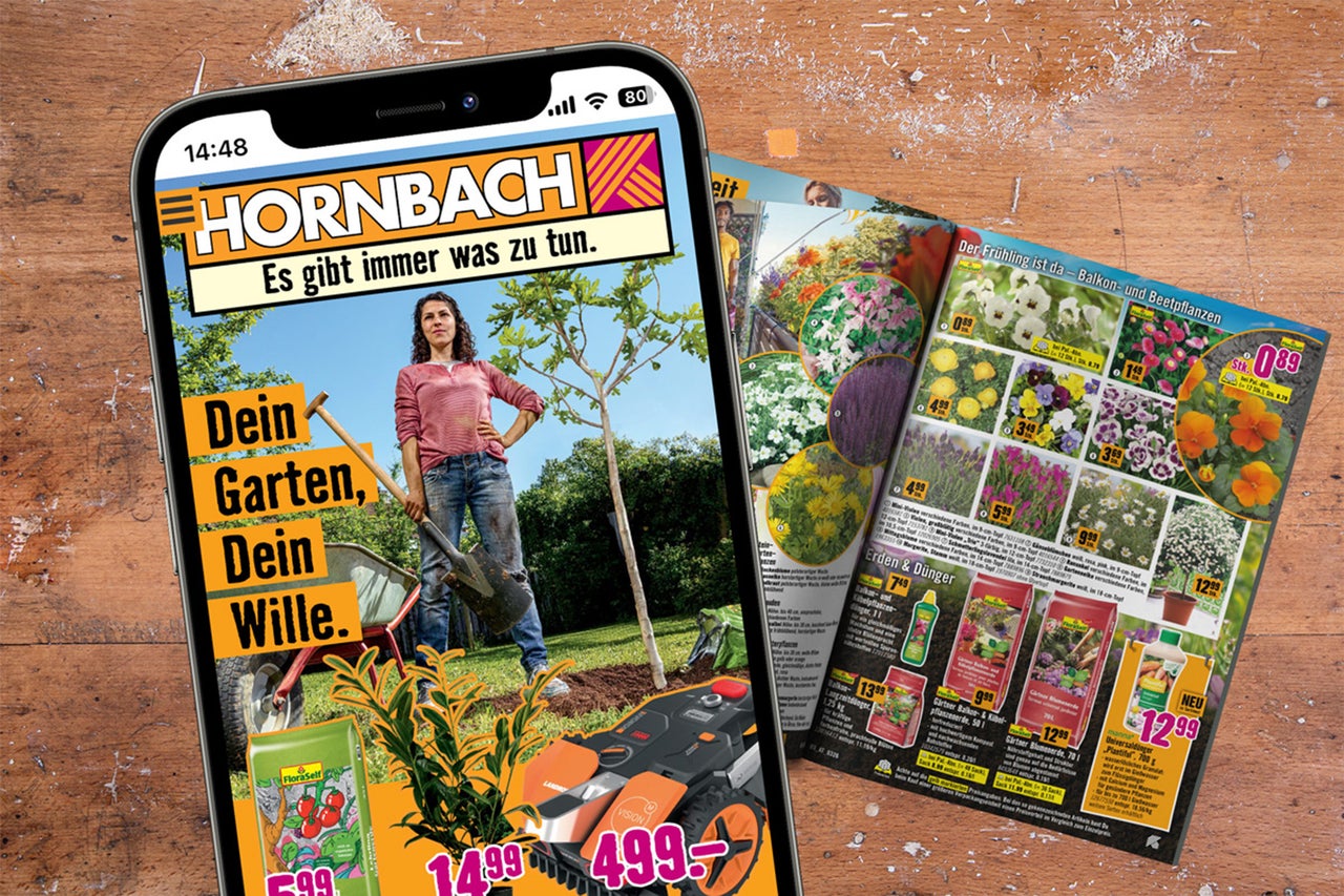 Smartphone mit Hornbach App und Hornbach Logo zeigt eine Frau im Garten neben einem Hornbach Katalog mit Pflanzen und Erde auf Holz.