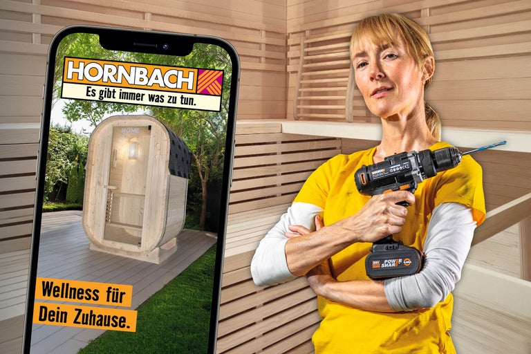 Eine Person hält einen Akkuschrauber in einer Holzsauna, während auf einem Smartphone eine Fasssauna von Home Deluxe in einem Garten zu sehen ist.