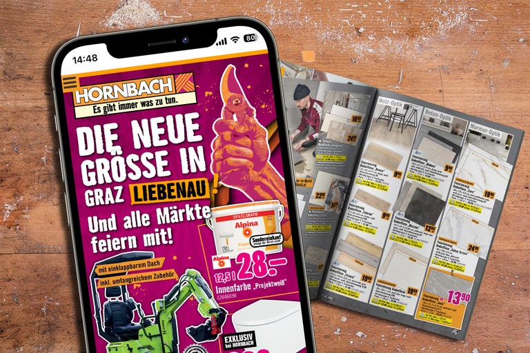 Smartphone zeigt Hornbach Werbeprospekt mit Angeboten für Fliesen und Alpina Innenfarbe auf einem Holztisch.