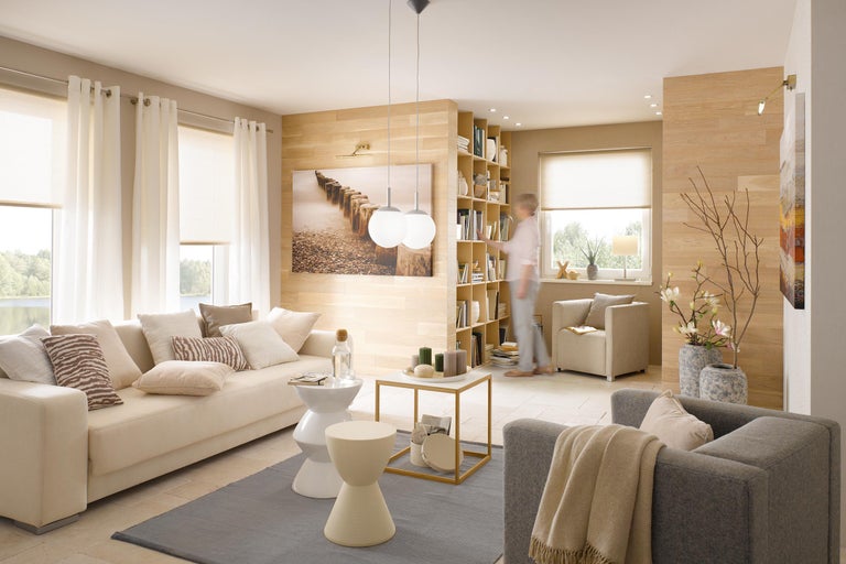 Wohnzimmer mit Sofa, Sessel, Bücherregal und Dekoration in hellen Farben