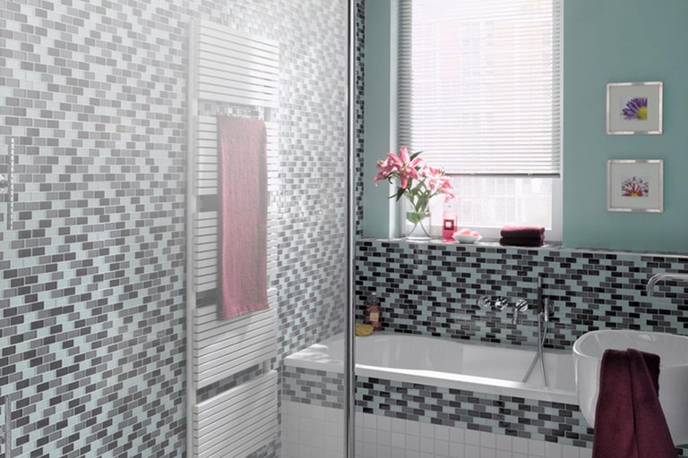 Badezimmer mit Mosaikfliesen, Badewanne und Handtuchwärmer