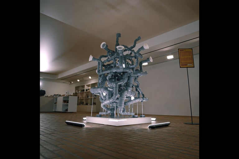 Installation aus grauen Kunststoffrohren auf einem weißen Podest in einem Raum