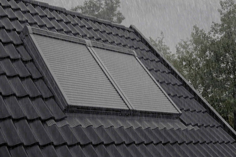 Dachfenster mit geschlossenem Rollladen bei Regen