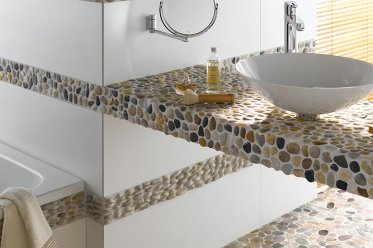 Modernes Badezimmer mit Waschtisch aus Naturstein, Spiegel und Armatur.