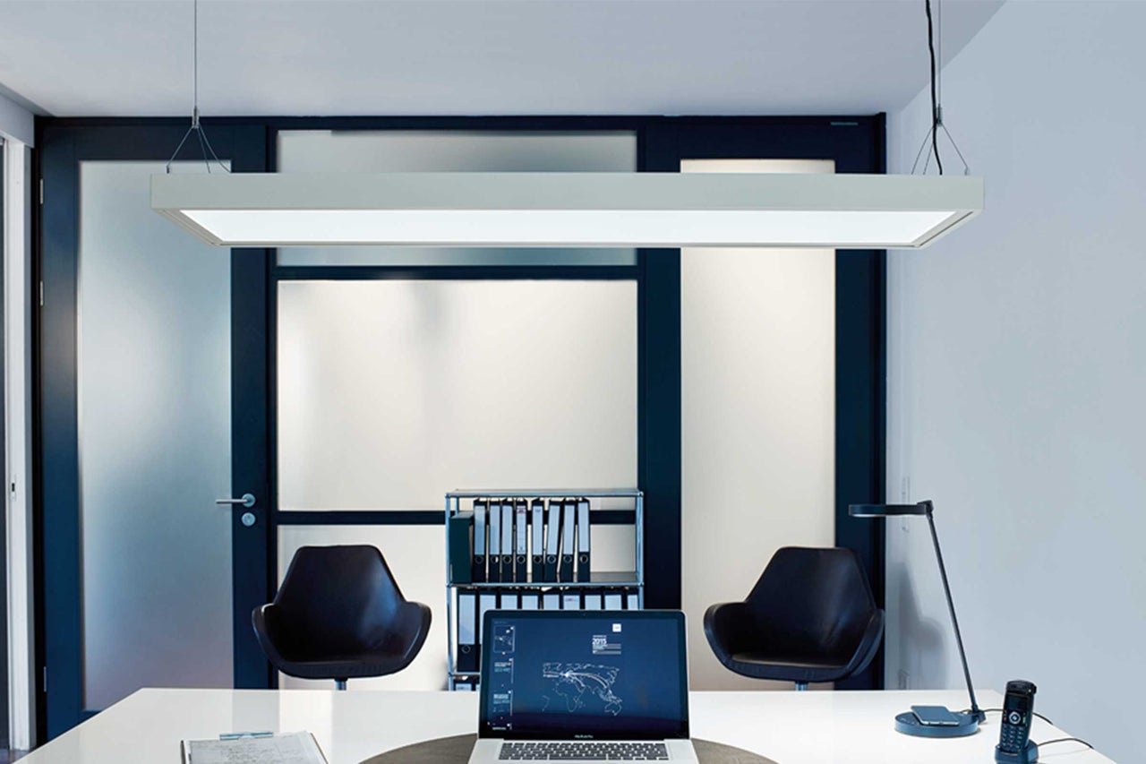 Büro mit Schreibtisch, Stühlen, Regalen, Tischleuchte und LED-Hängeleuchte