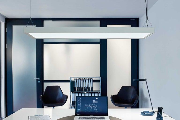 Büro mit Schreibtisch, Stühlen, Regalen, Tischleuchte und LED-Hängeleuchte