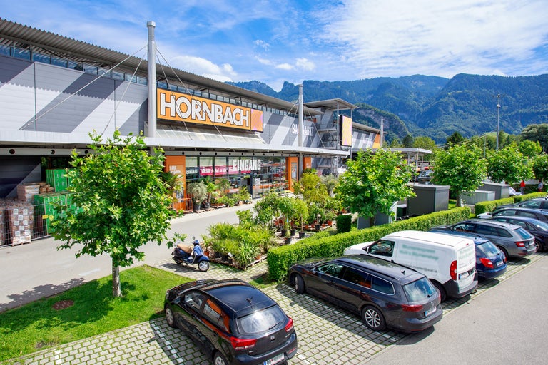 Außenansicht eines Hornbach Baumarkts mit Parkplatz und Bergen im Hintergrund