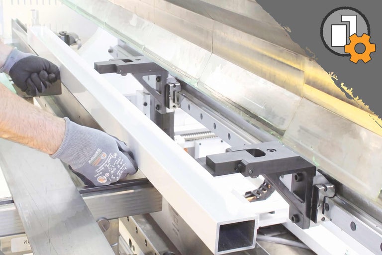 Person mit Arbeitshandschuhen bearbeitet ein weißes Metallprofil in einer Abkantpresse im Rahmen des Zuschnittservice