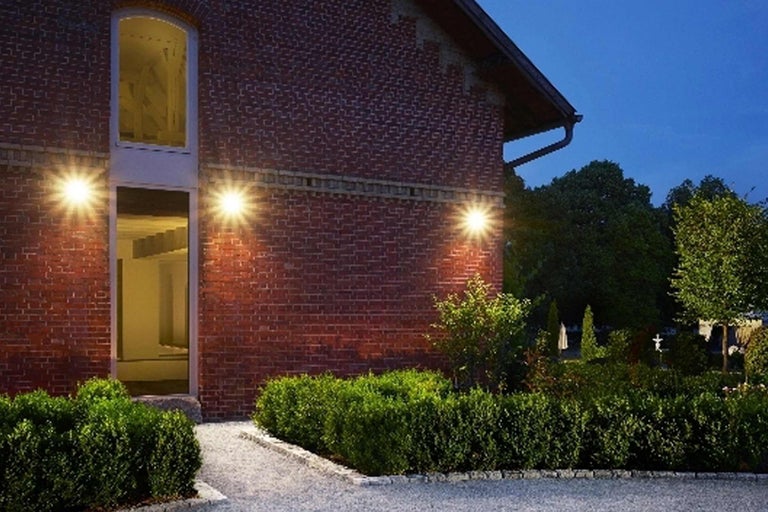 Außenansicht eines Backsteingebäudes mit Gartenbeleuchtung