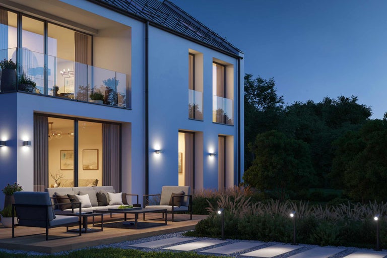 Außenansicht eines modernen Hauses mit Gartenmöbeln und Außenbeleuchtung am Abend