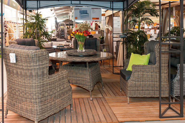Gartensitzgruppe mit Rattansesseln und rundem Tisch unter einem Pavillon.