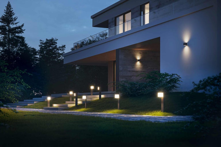 Außenansicht eines modernen Hauses mit Gartenbeleuchtung entlang eines Weges und an der Hauswand