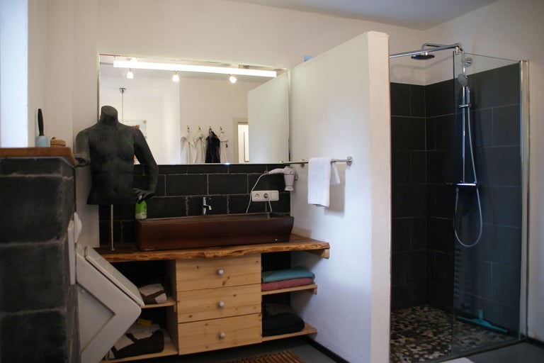 Badezimmer mit Waschtisch aus Holz, Spiegel, Dusche und Dekoration