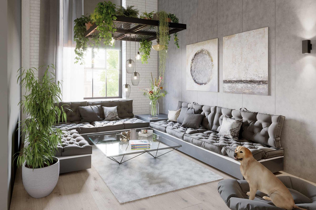 Wohnzimmer mit grauer Sitzgruppe, Glascouchtisch und Dekorationen wie Pflanzen und Bildern