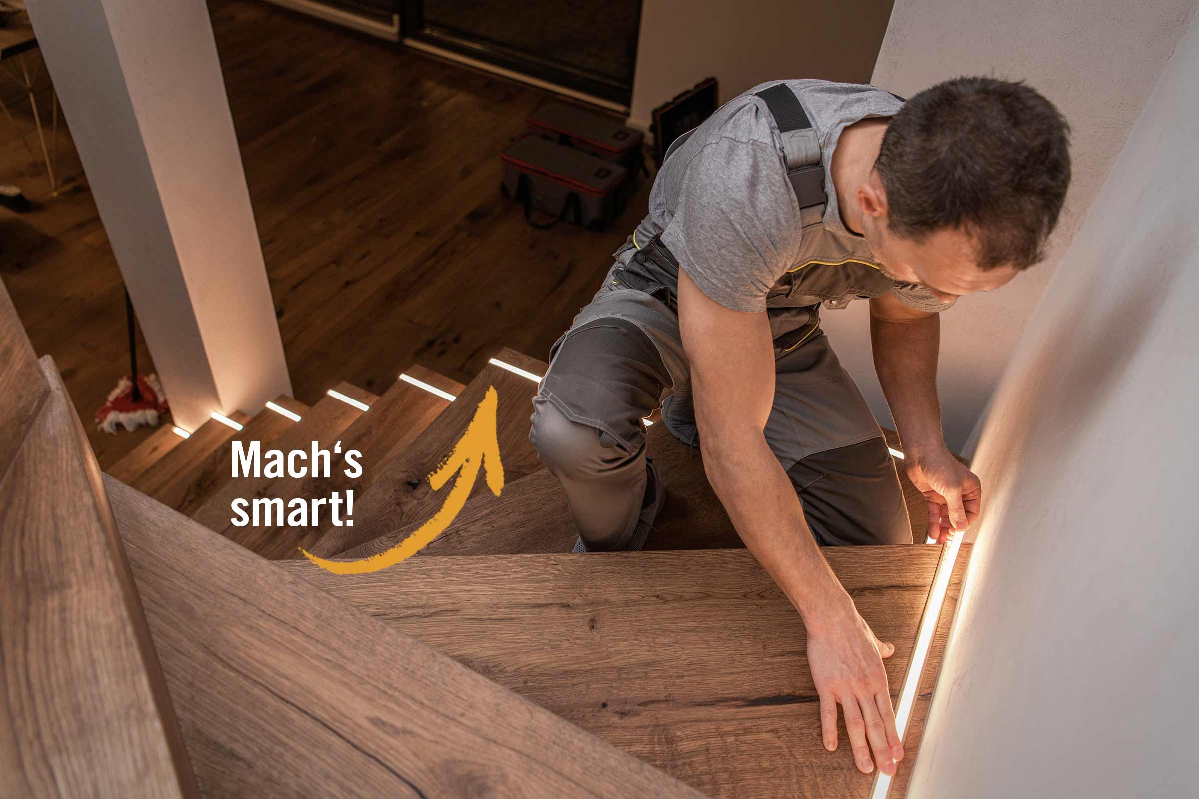 Ein Handwerker befestigt LED Streifen an einer Holztreppe.