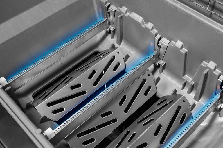 Innenansicht eines Gasgrills mit Brennern und Flammenverteilern.