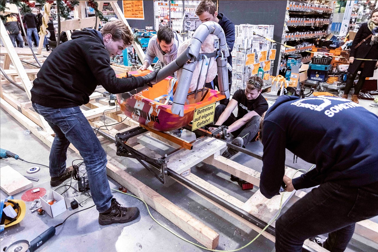 Gruppe von Personen, die an einem Bobschlitten auf einem Holzrahmen arbeiten