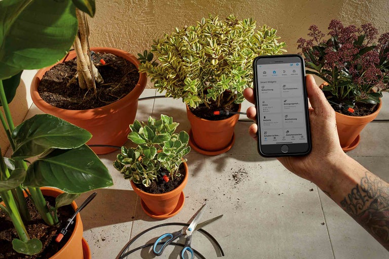 Pflanzenbewässerungssystem mit Smartphone-App Steuerung in einem hellen Raum