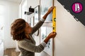 Frau richtet Bilderrahmen mit Wasserwaage an der Wand aus.