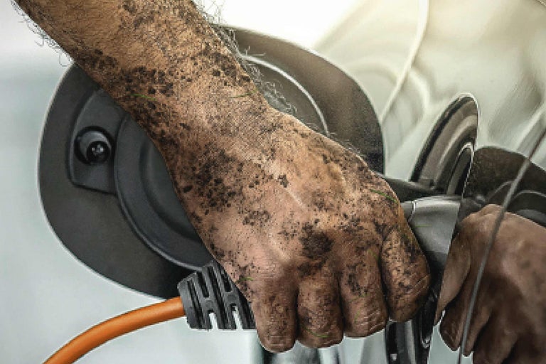 Eine schmutzige Hand schließt ein Elektrokabel an ein Elektrogerät an