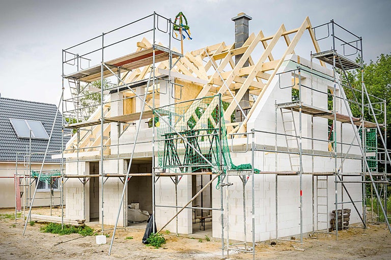 Rohbau eines Hauses mit Gerüst und Richtkranz