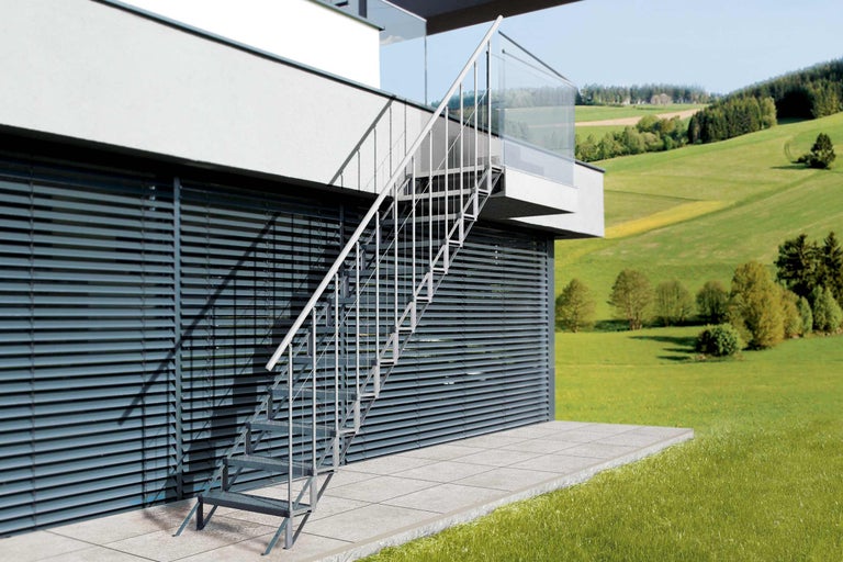 Außentreppe aus Metall mit Geländer an einem modernen Haus.