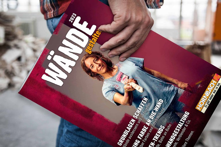 Ein Mann hält das Hornbach Magazin Wände Gestalten 2023 in der Hand. Das Magazin behandelt Themen wie Wandgestaltung und Farbtrends.