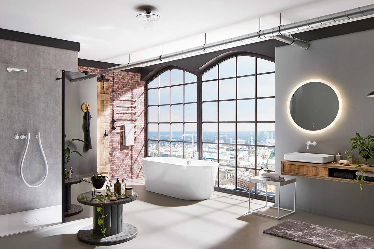 Badezimmer im Loftstil mit Badewanne, Dusche und Waschtisch vor einem großen Fenster mit Stadtblick