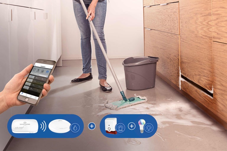 Frau wischt Wasser in der Küche, gesteuert mit Smartphone und dem Smart Home System von Hornbach