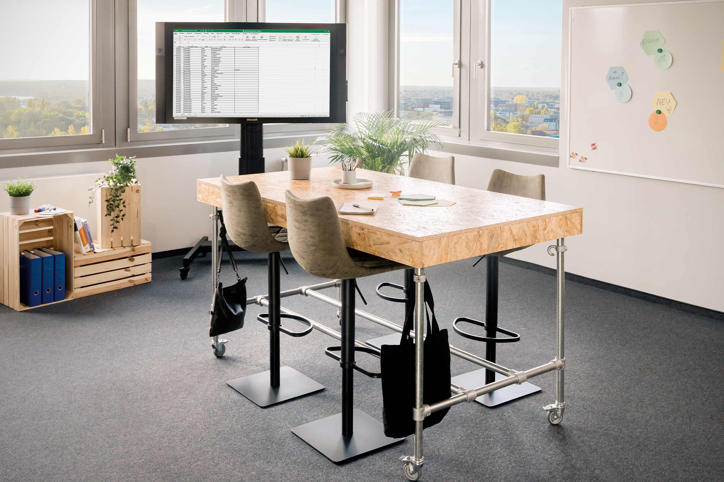 Büro mit Tisch aus Holzwerkstoff, Monitor, Stühlen und Whiteboard für die Zusammenarbeit