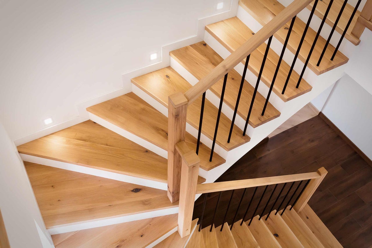 Holztreppe mit schwarzem Geländer in hellem Interieur