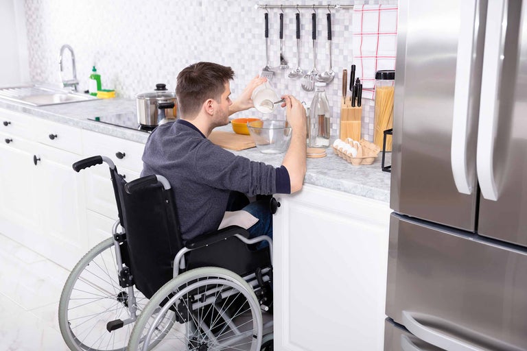 Mann im Rollstuhl backt in einer zugänglichen Küche