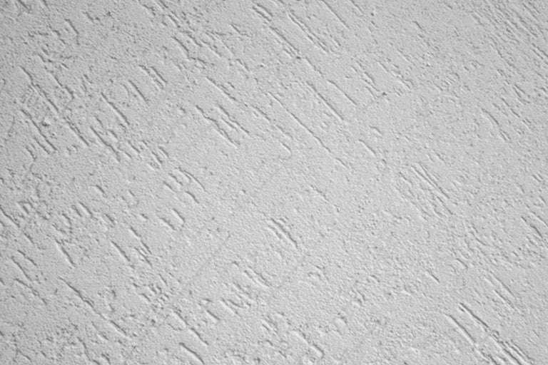 Nahaufnahme einer Wand mit Kratzputzstruktur.