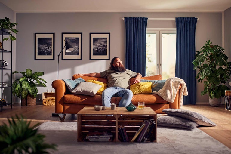 Wohnzimmer mit Ledersofa, Kissen, Couchtisch und Zimmerpflanzen