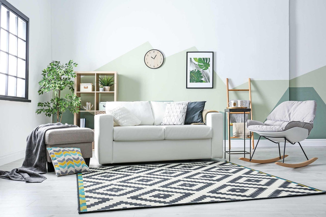 Wohnzimmer mit Sofa, Sessel, Teppich und Dekoration