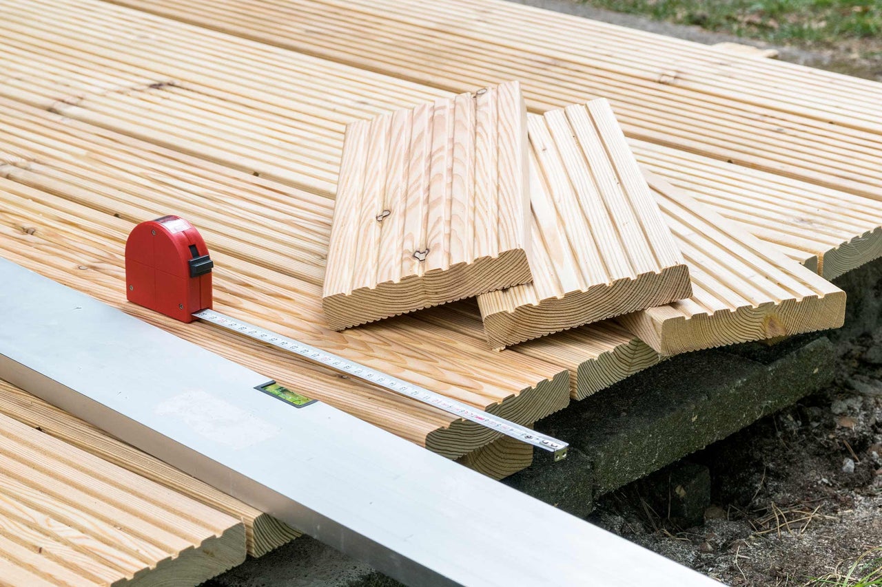 Aufbau einer Holzterrasse mit Terrassendielen, Wasserwaage und Rollbandmaß