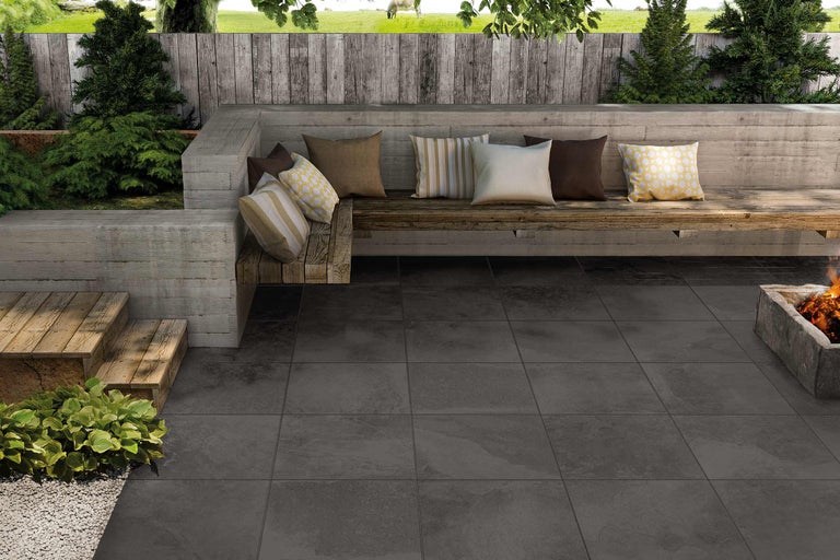 Terrasse mit grauen Fliesen, Sitzbank und Feuerstelle