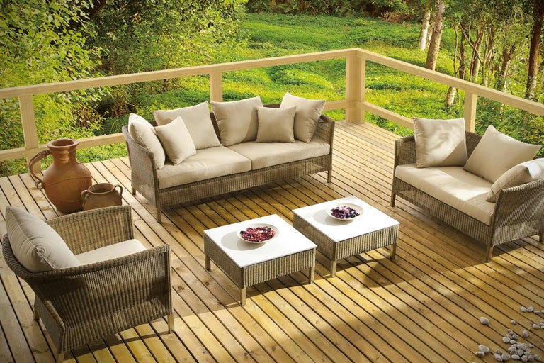 Terrasse mit Rattanmöbeln, bestehend aus Sofa, Sesseln und Tischen