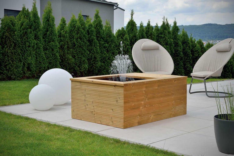 Gartenszene mit Holzbrunnen, Gartenleuchten und Gartenstühlen