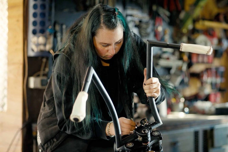Frau montiert einen Motorradlenker in einer Werkstatt