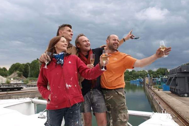Vier Personen mit Sektgläsern auf einem Boot, möglicherweise feiernd