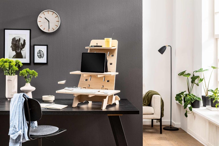 Arbeitszimmer mit höhenverstellbarem Schreibtischaufsatz aus Holz, Tablet und Büromaterialien