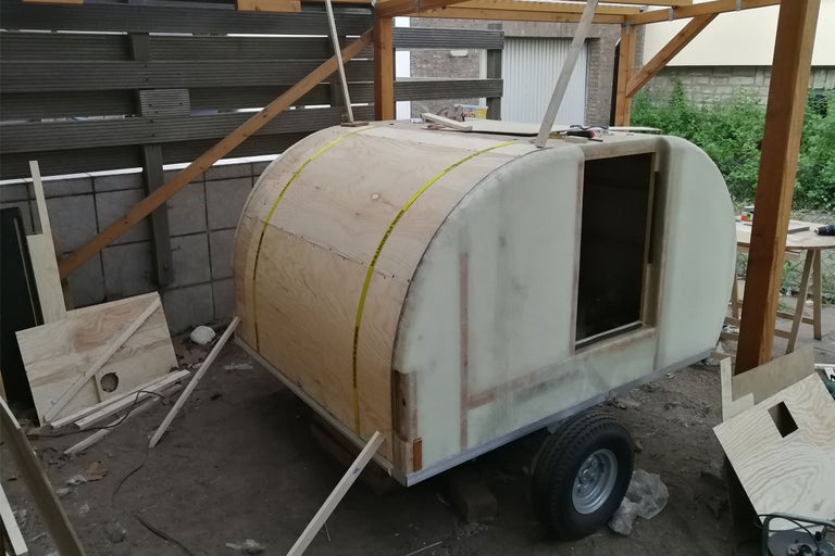 Unfertiger Wohnwagen aus Holz und anderen Materialien auf einem einzelnen Rad montiert