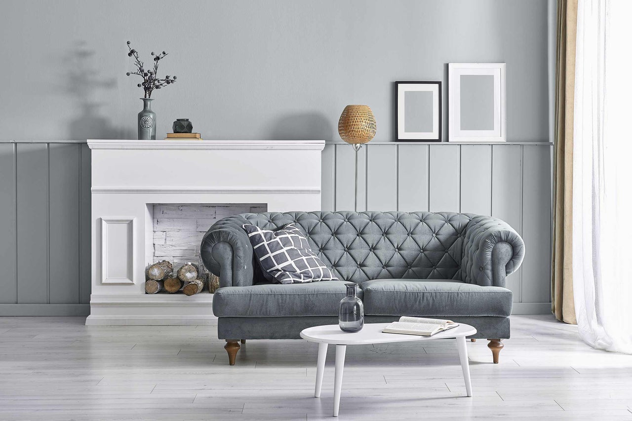 Wohnzimmer-Szene mit grauem Sofa, weißem Kamin und rundem Tisch