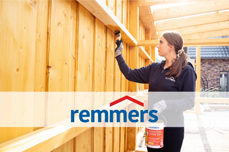 Eine Frau streicht Holz mit einer Holzschutzcreme von Remmers